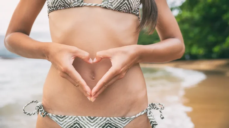 Photo d'une femme sur la plage en bonne santé intestinale faisant un coeur avec ses mains sur son ventre