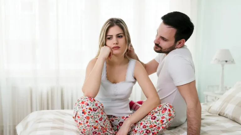 Photo d'un couple assis sur un lit frustré dû à des troubles sexuels